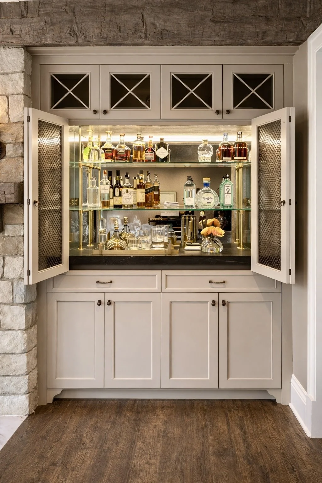 A custom built-in bar with brass poles, glass shelves and an antique mirror backsplash.